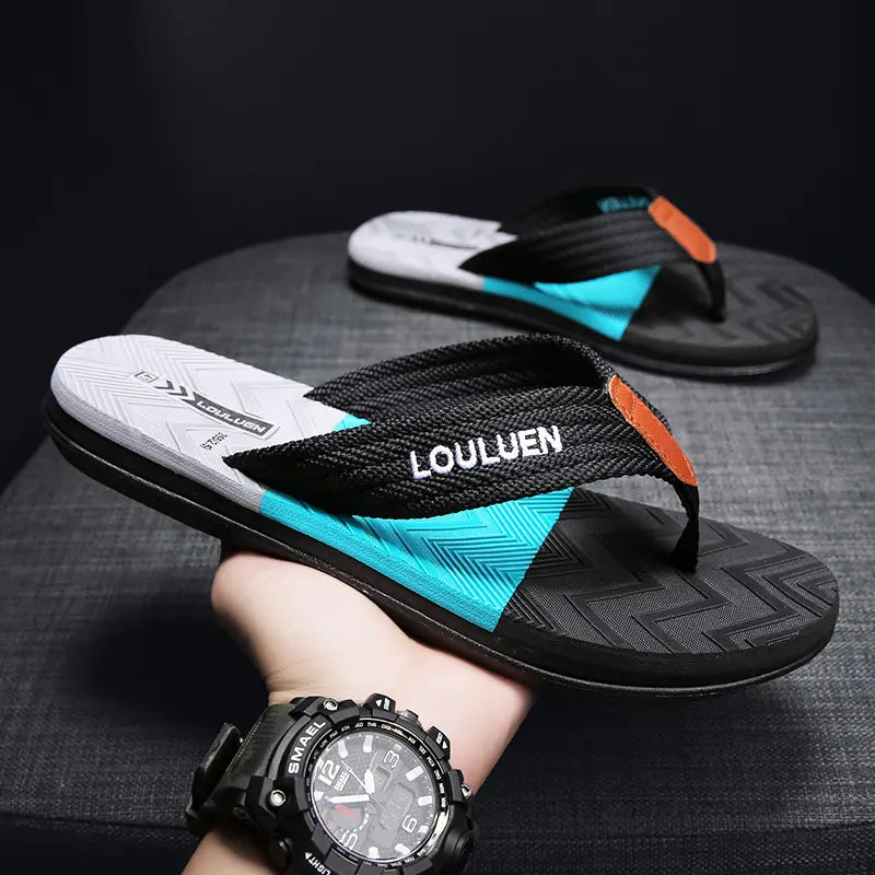 Men's black Y-strap flip-flops featuring a turquoise accent panel and white 'LOULUEN' embroidery, presented on a textured grey footbed and black zig-zag tread outsole.