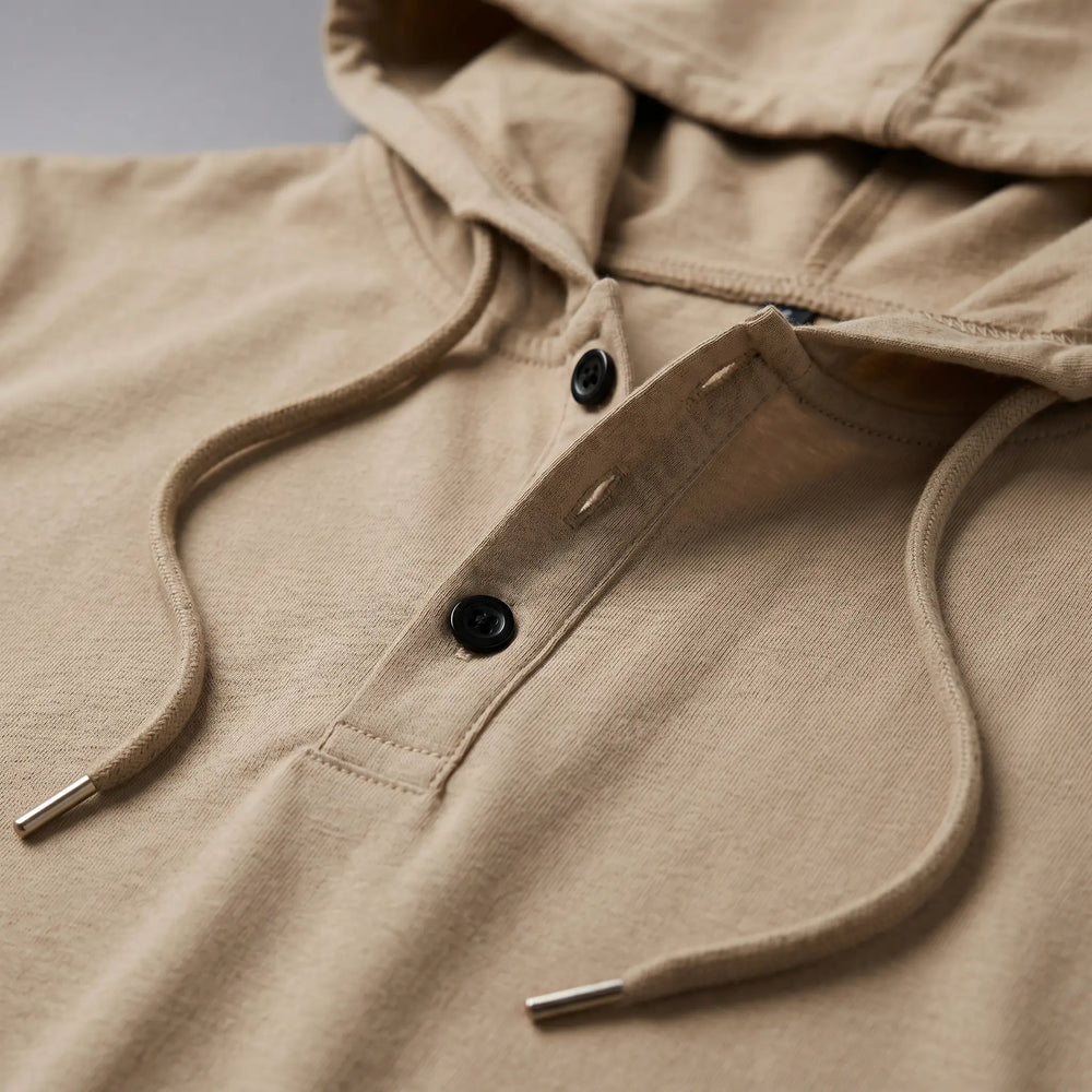 Close-up of a men's short-sleeve hooded tee in Desert Khaki, showcasing the matte black two-button henley placket and drawstrings with metal tips.