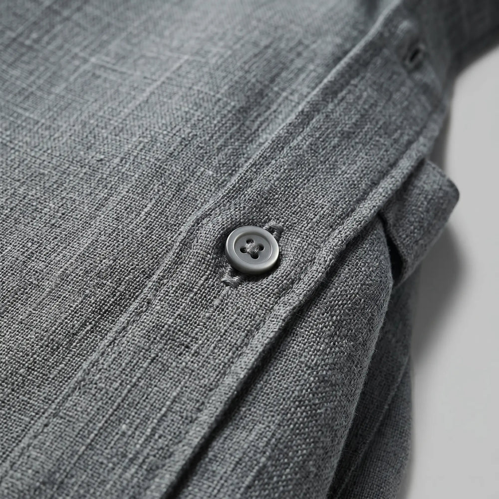 Close-up view of a medium grey men's relaxed fit shirt, showcasing the slub texture of the cotton-linen blend fabric and a tonal button closure.