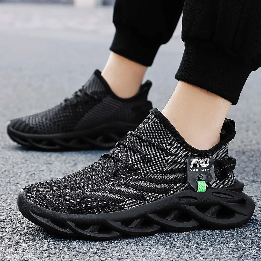 Black Mikari breathable knit sneakers with a sculpted light tan sole, shown from a three-quarter side view on a person&