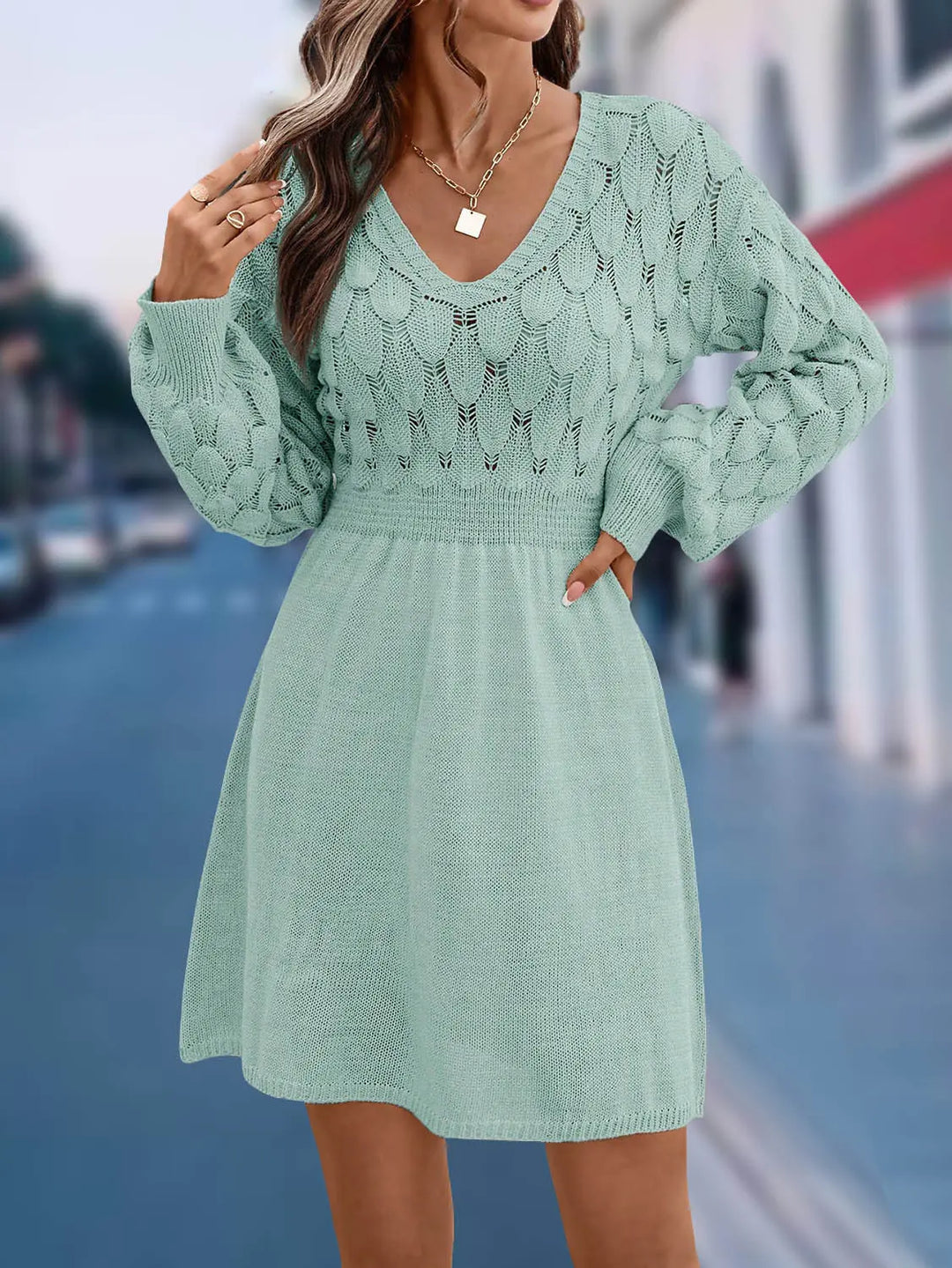 Model wearing a light mint green V-neck A-line knit dress with intricate diamond and cable patterns on the bodice and balloon sleeves, cinched waist, and mid-thigh hem.