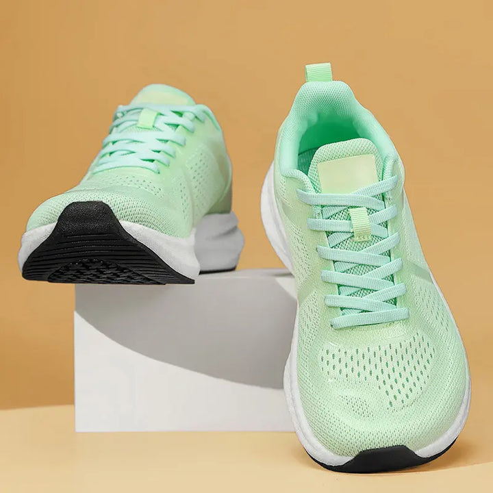 Light mint green wide fit breathable athletic trainers with a mesh upper and white EVA midsole, shown from a three-quarter side view.