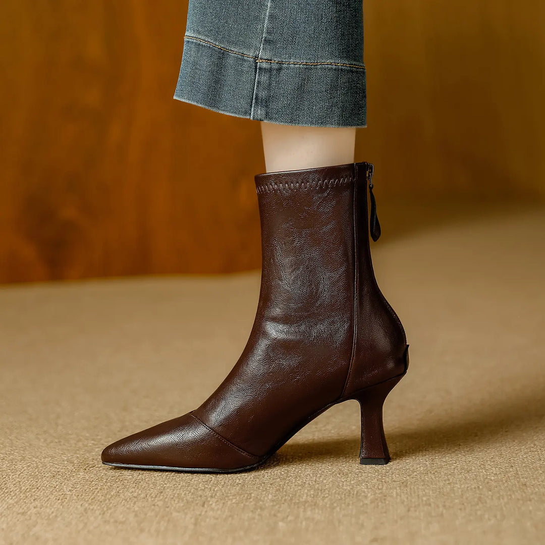 Side view of a chic dark brown faux leather ankle boot with a pointed toe and a slender stiletto heel, featuring a discreet back zipper closure.