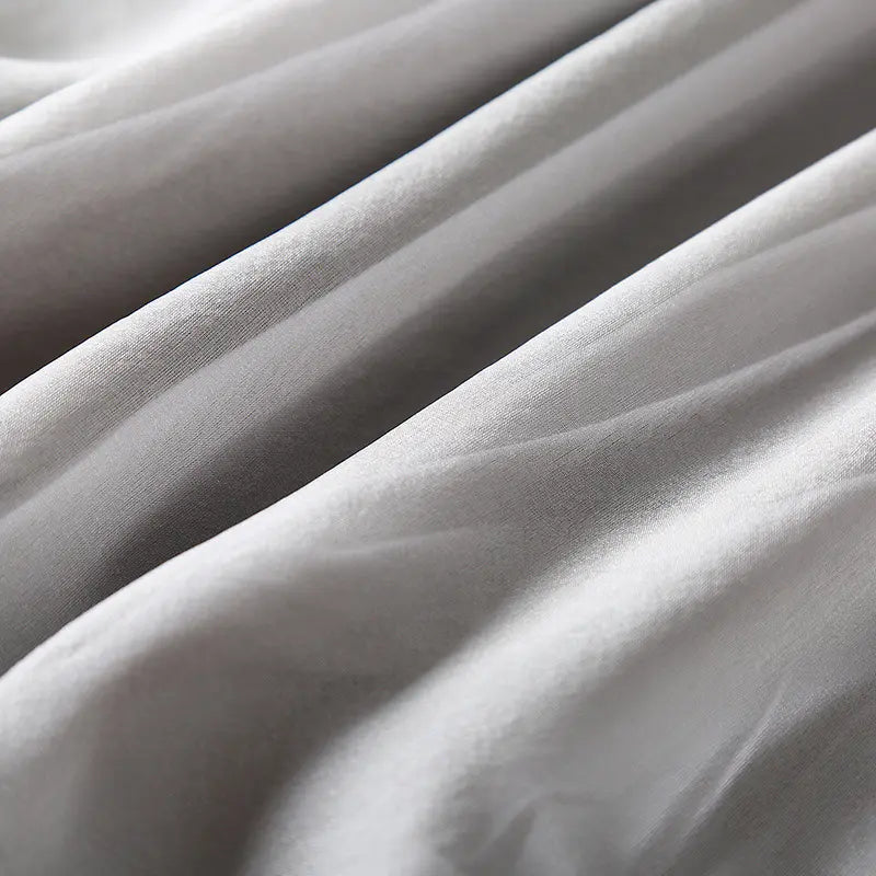 Close-up detail of muted grey pure silk fabric showing its natural sheen and fluid drape with soft folds.