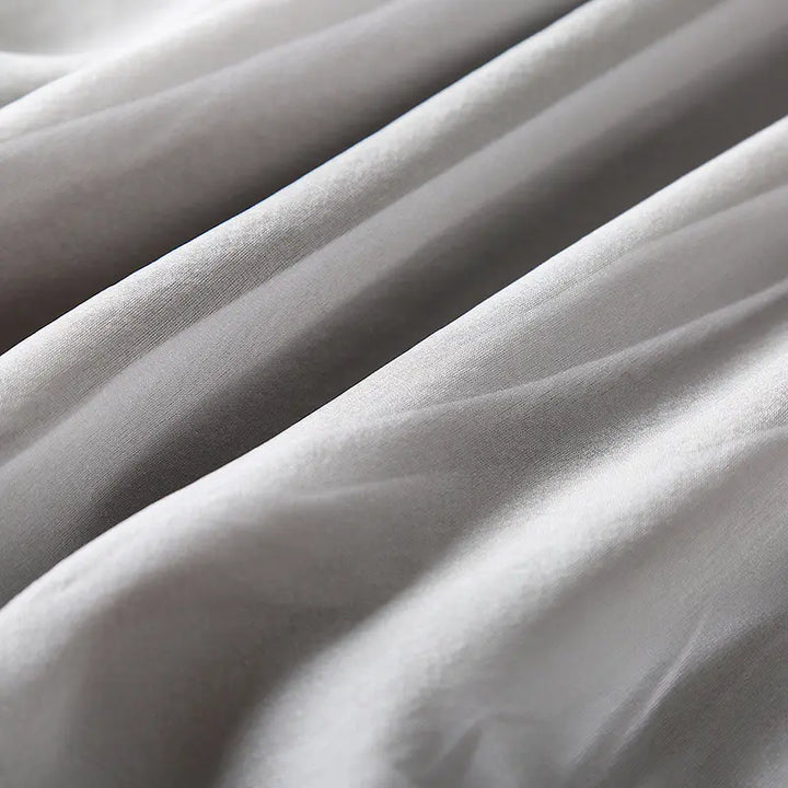 Close-up detail of muted grey pure silk fabric showing its natural sheen and fluid drape with soft folds.