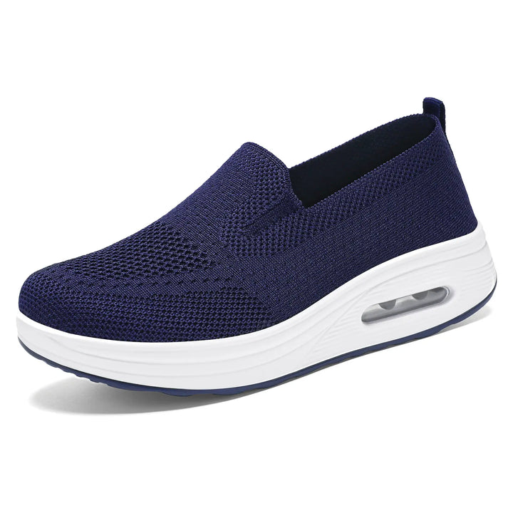 Dark navy blue breathable knit slip-on sneakers with a white platform sole and visible air cushion heel, shown in a three-quarter front view.