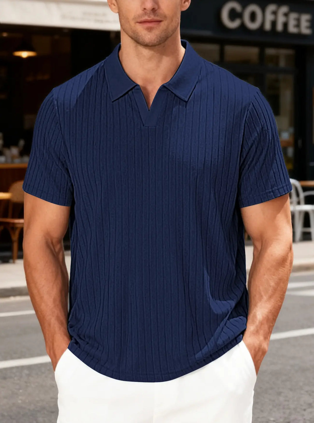 Navy blue textured knit V-neck polo shirt with short sleeves, worn by a man with hands in pockets in an outdoor casual setting.