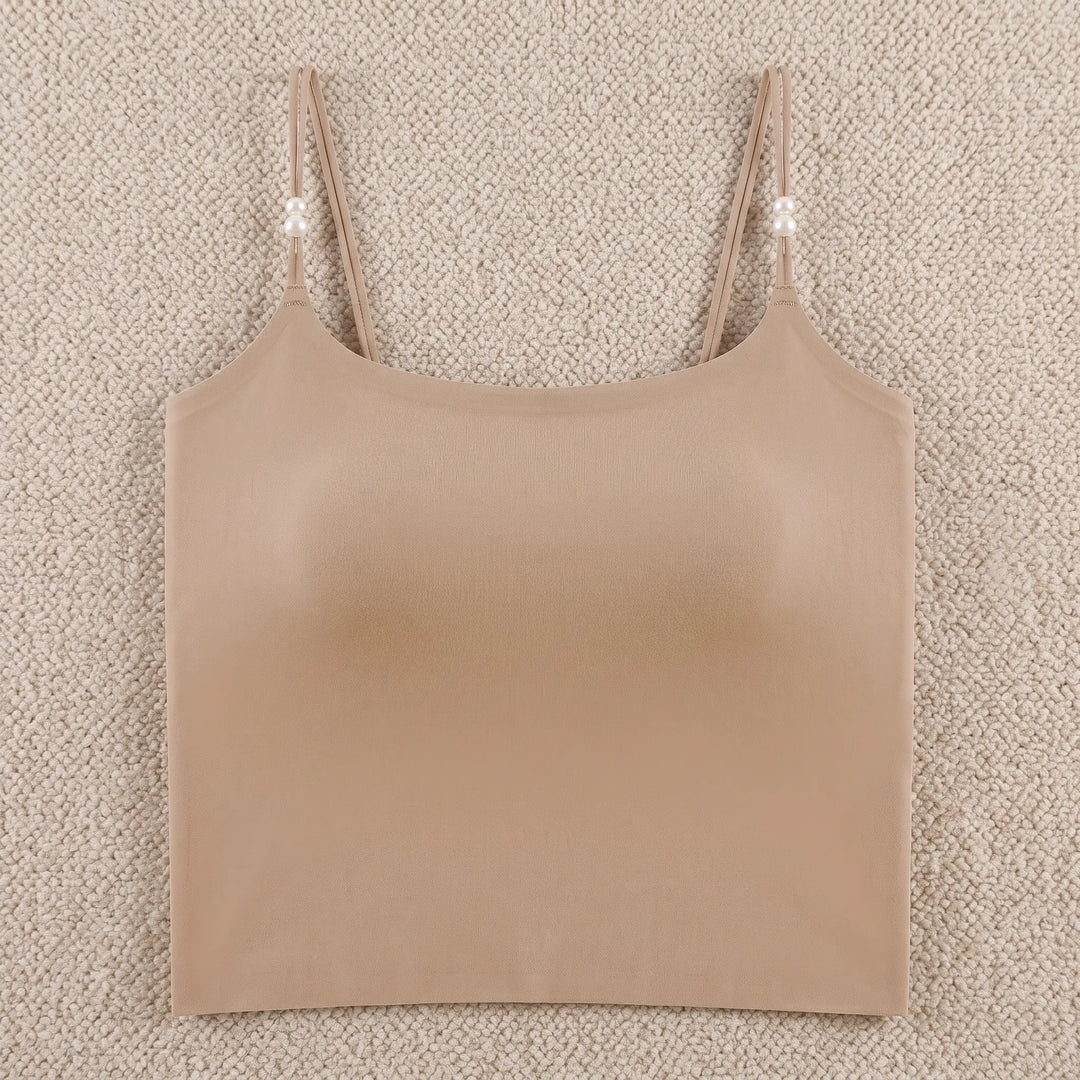 A nude, seamless camisole featuring adjustable spaghetti straps adorned with small pearl accents and a built-in 4cm molded cup for shaping. The camisole has a round neckline and a wide hemband, displayed flat on a white background.