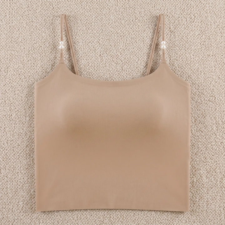 A nude, seamless camisole featuring adjustable spaghetti straps adorned with small pearl accents and a built-in 4cm molded cup for shaping. The camisole has a round neckline and a wide hemband, displayed flat on a white background.