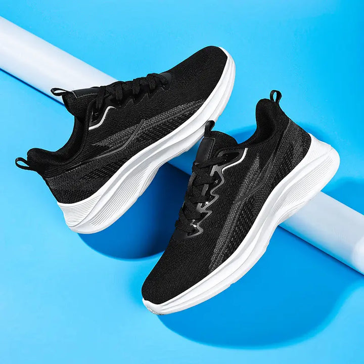 A pair of black Nyrvix lightweight running shoes with sculpted white soles and subtle gray accents, shown from a three-quarter angle against a vibrant blue studio background.