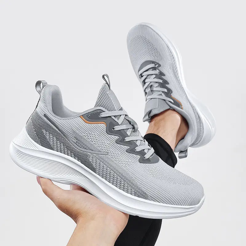 Nyrvix lightweight breathable running shoes in steel grey heathered knit with a sculpted white foam sole and orange accents, shown from a three-quarter angle.