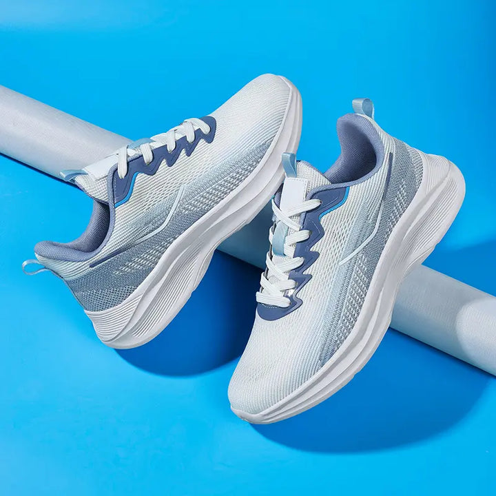 Nyrvix Steel Grey lightweight breathable running shoes shown from a three-quarter angle, featuring a heathered knit upper, sculpted white foam midsole, and blue accents.