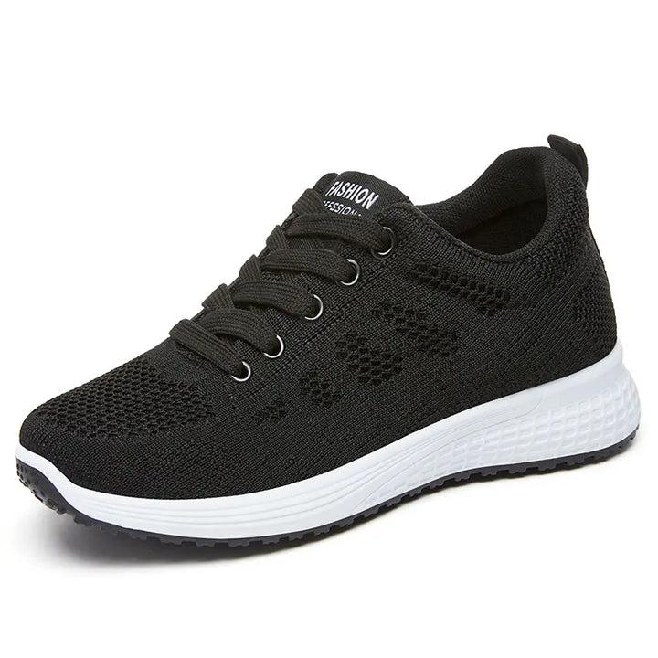 Black Nyxos breathable knit low-top athletic sneaker with a geometric pattern, pink interior lining, and white textured midsole, presented in a three-quarter view.