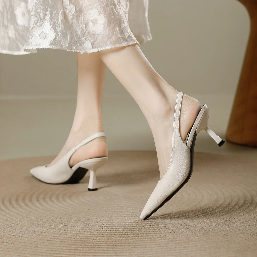 Off-white pointed-toe slingback heels with a sculpted stiletto heel, shown in motion on a person&