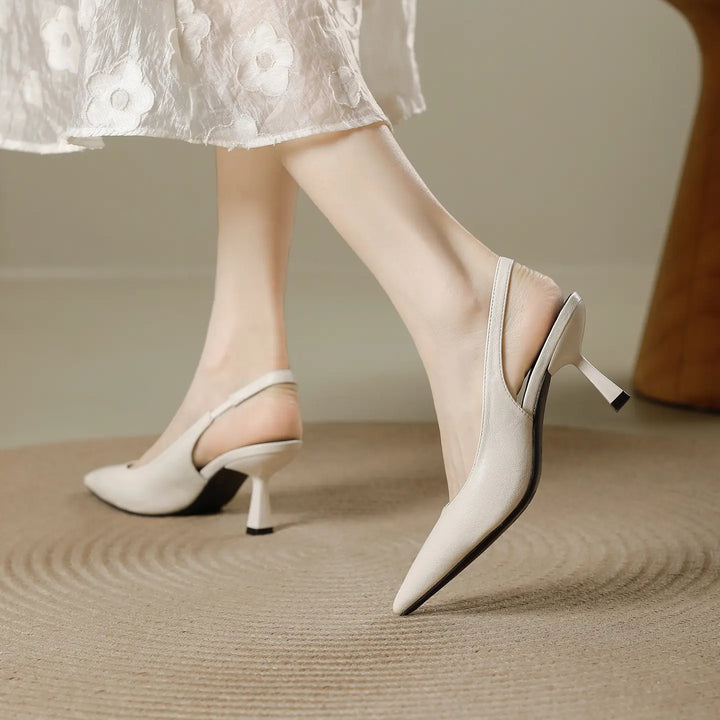 Off-white pointed-toe slingback heels with a sculpted stiletto heel, shown in motion on a person&