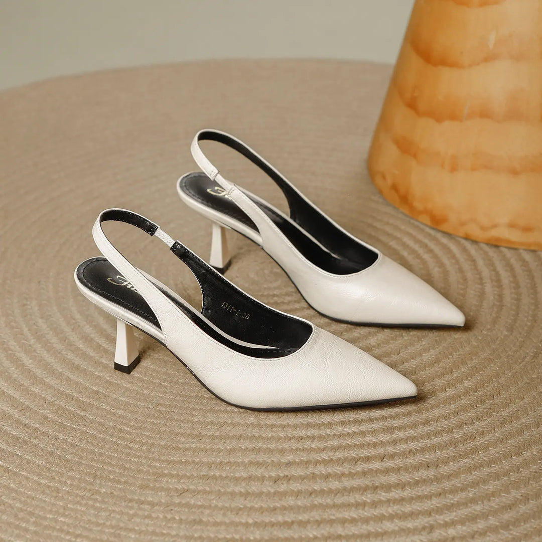 Off-white pointed-toe slingback heels with a sculpted stiletto heel and elasticated strap, shown from a three-quarter angle.