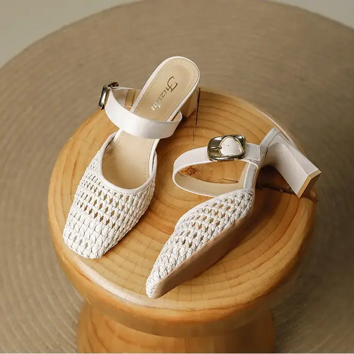 Pair of off-white woven square toe block heel mules with adjustable gold-tone buckle straps, shown from a three-quarter angle on a wooden stool.