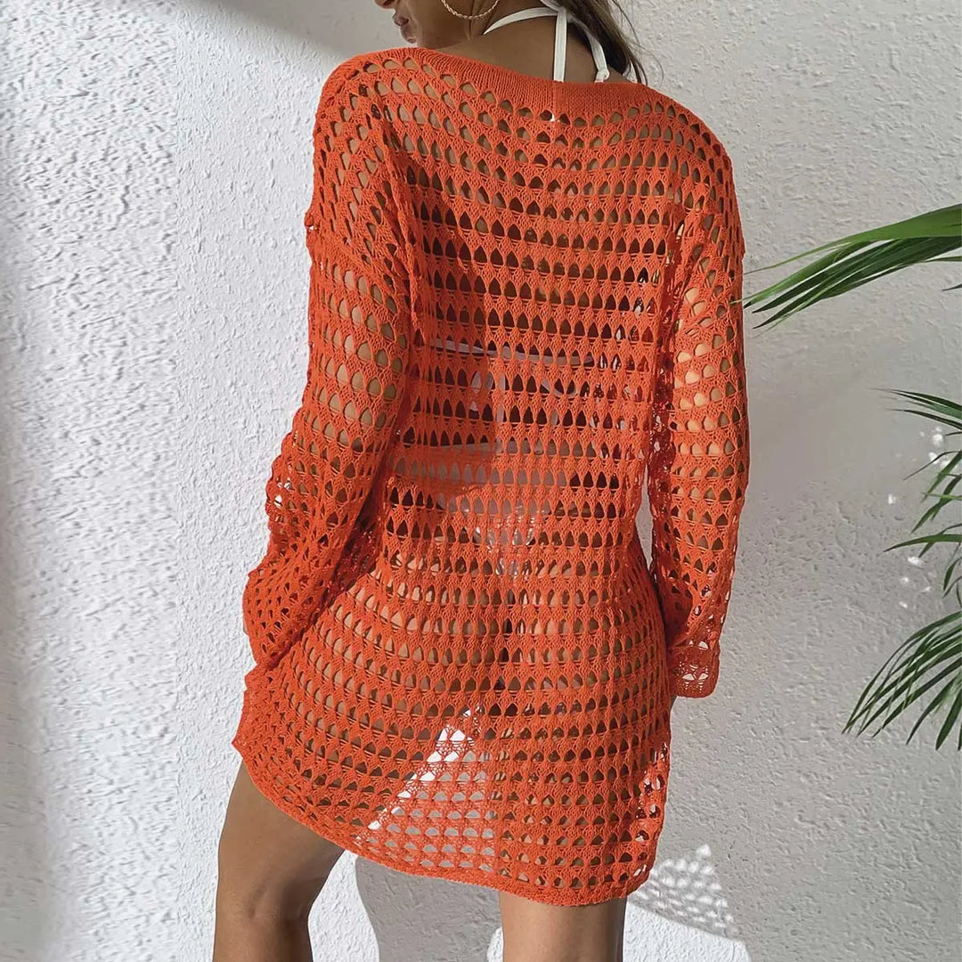 Back view of a woman wearing an orange crochet beach cover-up dress with an intricate open-knit pattern over white swimwear.