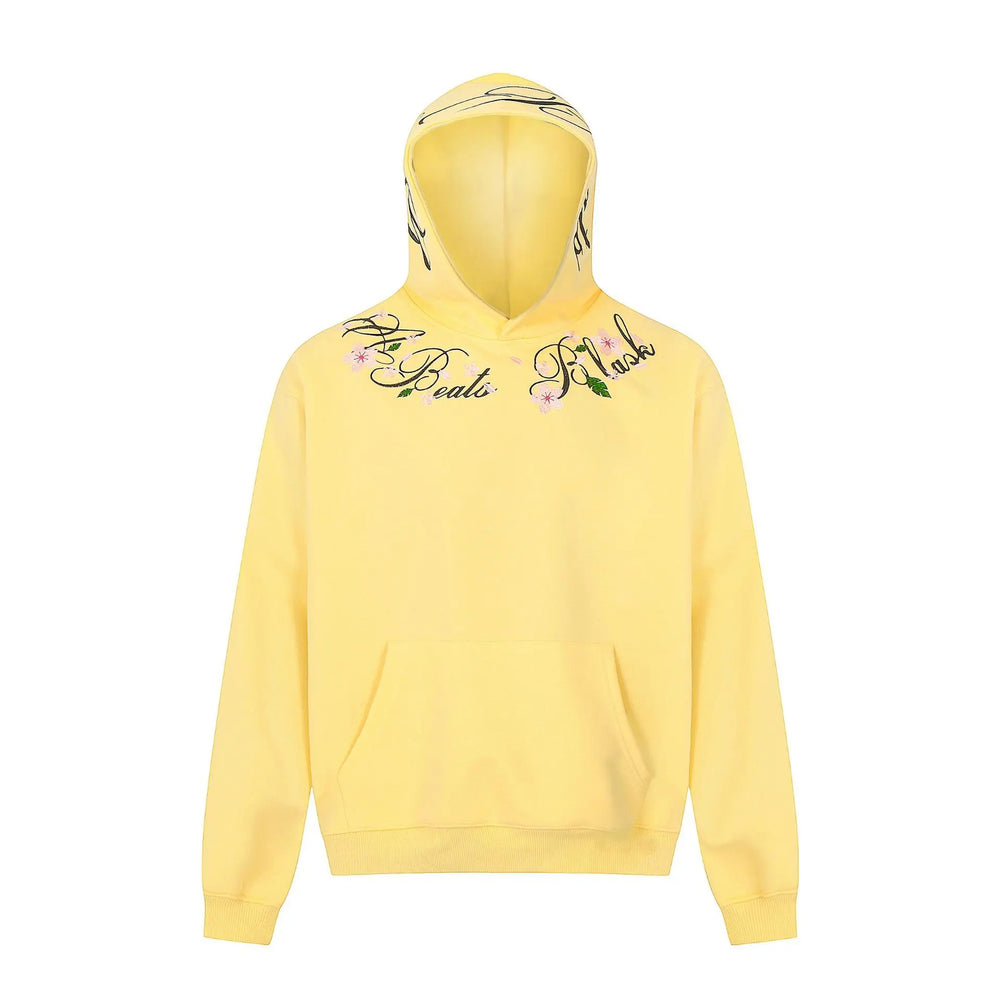 Sunny Marigold yellow Orvela hoodie featuring intricate floral and script embroidery around the neckline, with a relaxed fit, dropped shoulders, and a kangaroo pocket.