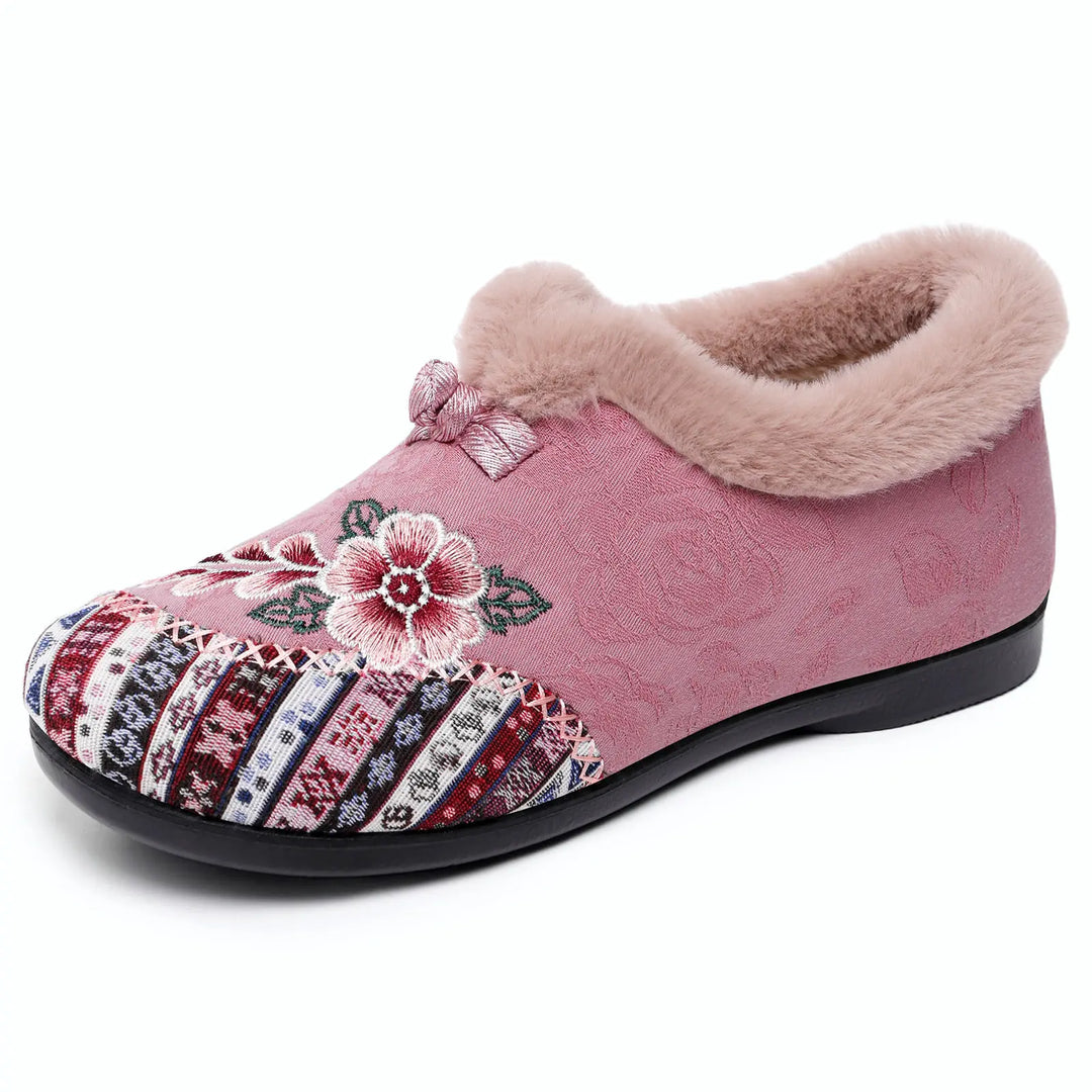 Pink embroidered mule slippers for women featuring a plush faux-fur trim, intricate floral detailing on the vamp, and a woven patterned toe box.