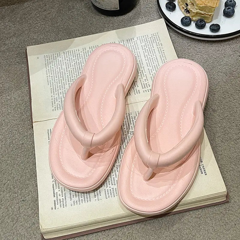 Light pink EVA flip-flops with padded thong straps, artfully arranged on an open book with visible text.