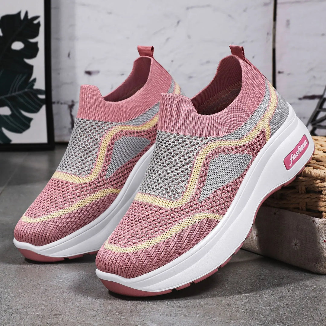 Vibrant pink slip-on knit sneakers with grey and yellow wavy stripe detailing and a white platform sole featuring a pink &