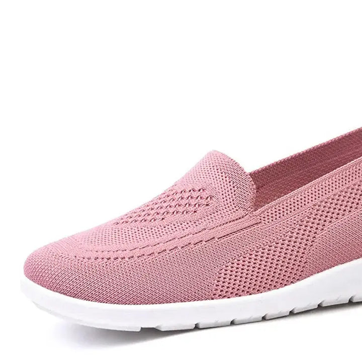 Pink breathable knit slip-on trainer shoe with a subtle diamond weave pattern on the vamp and a clean white sole, featuring a heel loop.
