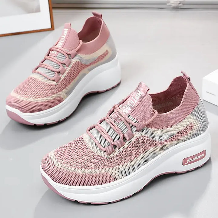 Three-quarter view of blush pink engineered knit platform trainers with a striped pattern, featuring grey laces, a chunky white sole, and &