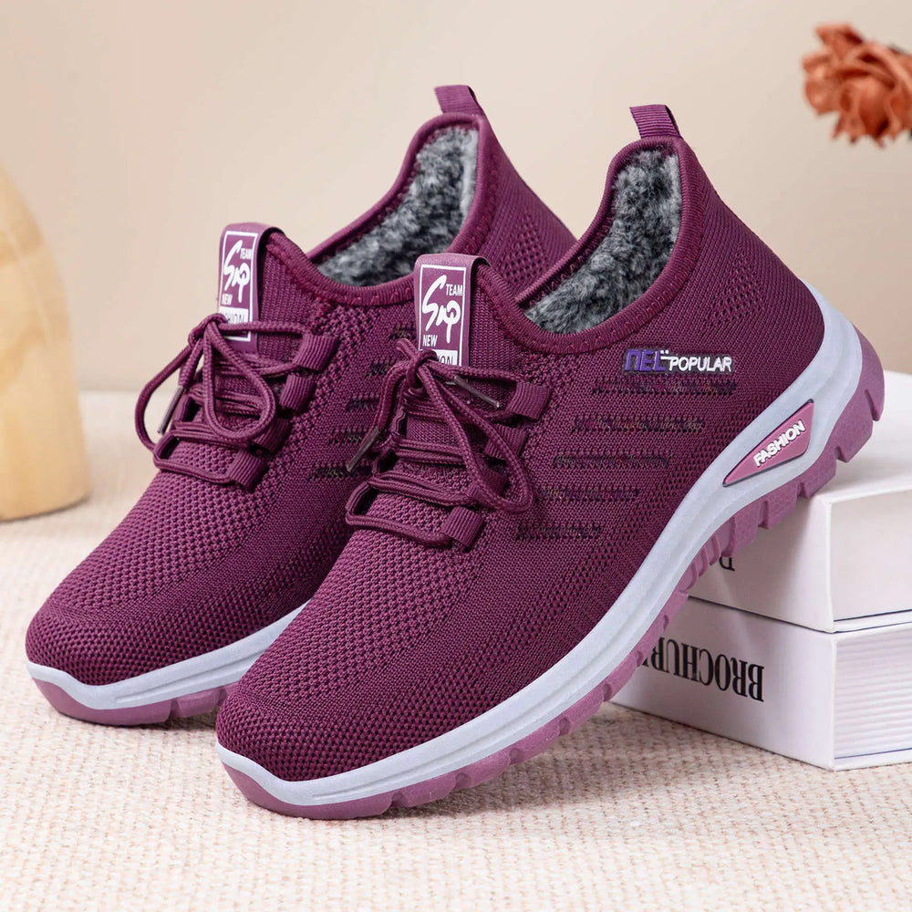 Deep purple knitted women's winter boots with plush faux fur lining, white midsole, and a secure lace-up closure, presented from a three-quarter angle.