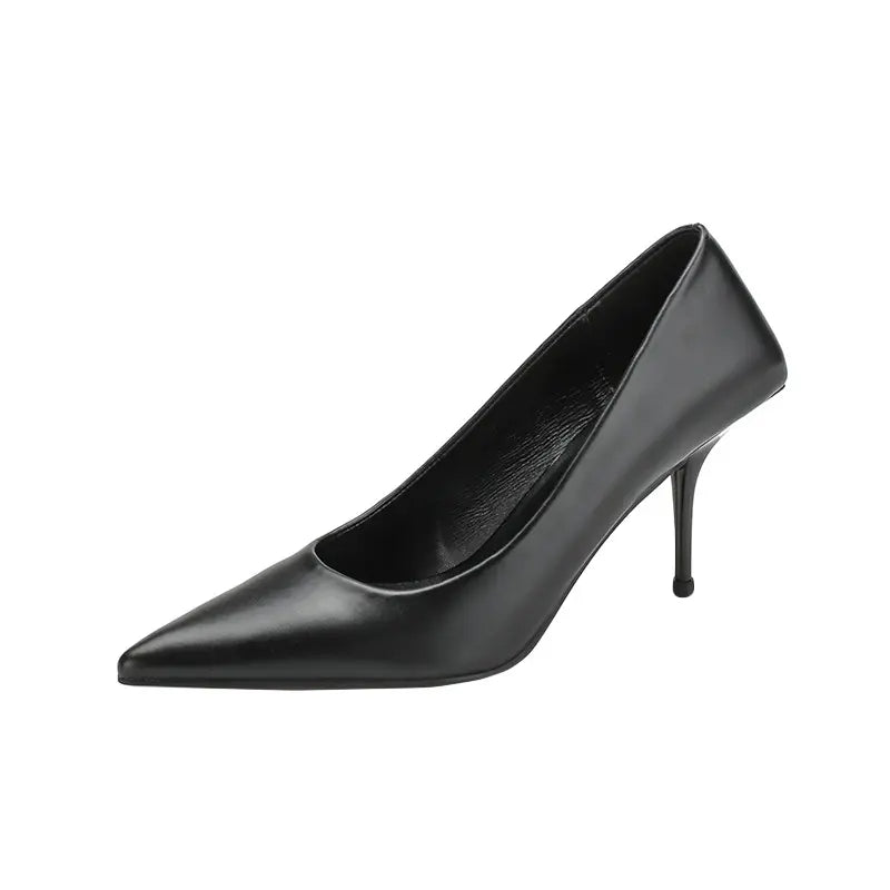 Side view of a black Qanari stiletto heel featuring a sharp pointed toe, high-gloss faux leather, and a slender sculpted heel.