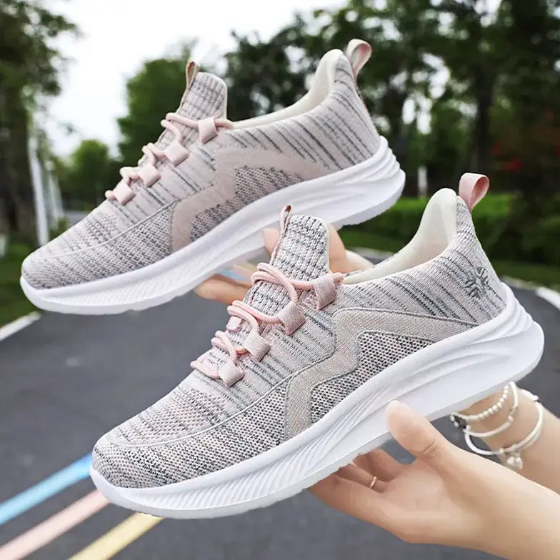 Qanik breathable mesh athletic trainers in dusty pink with grey knit texture and a contrasting wavy side graphic. Features pink laces, white sculpted soles, and heel/tongue pull tabs. Captured in a three-quarter view.