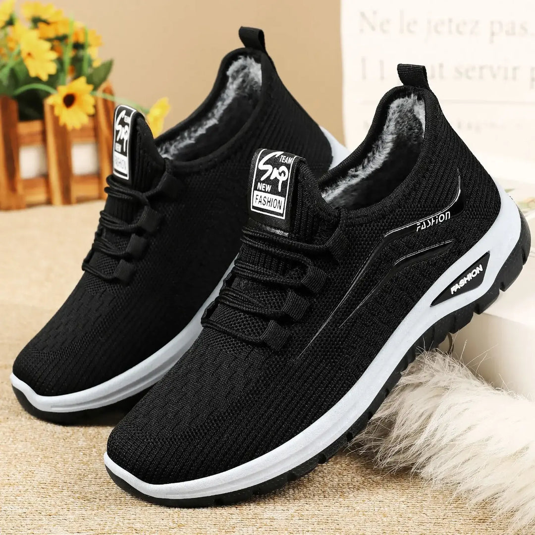 Three-quarter view of black Qorto warm winter sneakers featuring a breathable knit upper, plush fleece lining, white midsole, and durable outsole. Subtle &