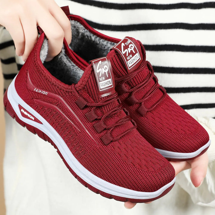 Three-quarter view of Qorto warm winter sneakers in deep red knit with white midsole and matching red outsole, showcasing plush faux fur lining and lace-up closure.