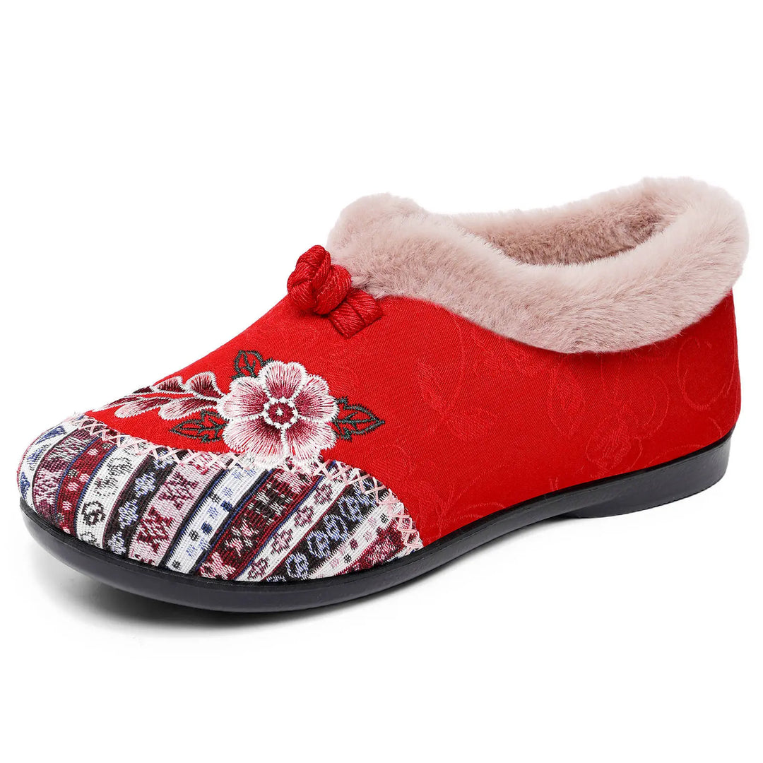 Red embroidered mule slipper with plush lining and decorative bow, showcasing detailed floral and geometric patterns on a white background.