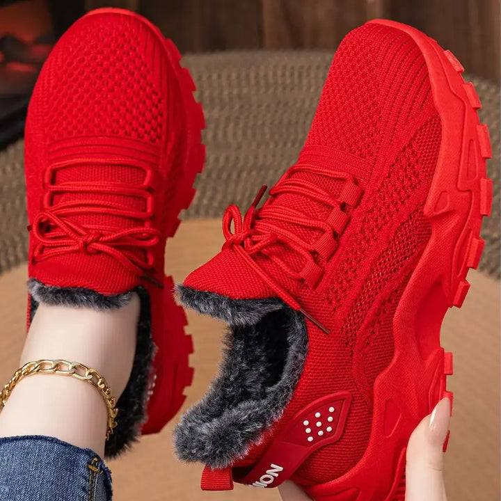 Red knit ankle boots with plush faux fur lining and a chunky platform sole, shown from a three-quarter angle with laces tied.