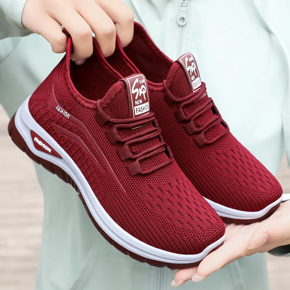 Crimson red breathable knit trainers for women, featuring a secure lace-up system and white midsole with a colored outsole. Side panel displays 'FASHION' in a lighter red.