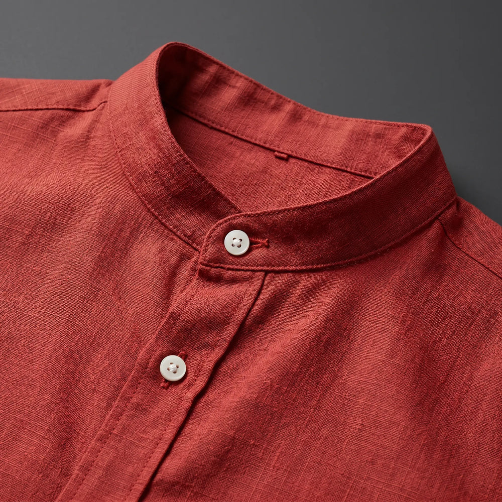 Close-up of a men's linen blend shirt in a deep reddish-brown hue, showcasing its mandarin collar and two opaque white buttons, highlighting the fabric's subtle texture.