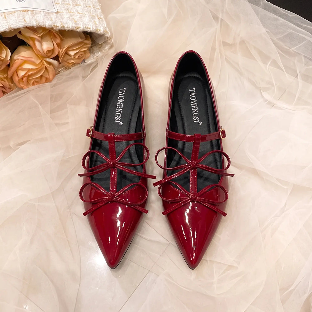 Pair of vibrant cherry red patent leather ballet flats with pointed toes, delicate multi-loop bows, and adjustable ankle straps.