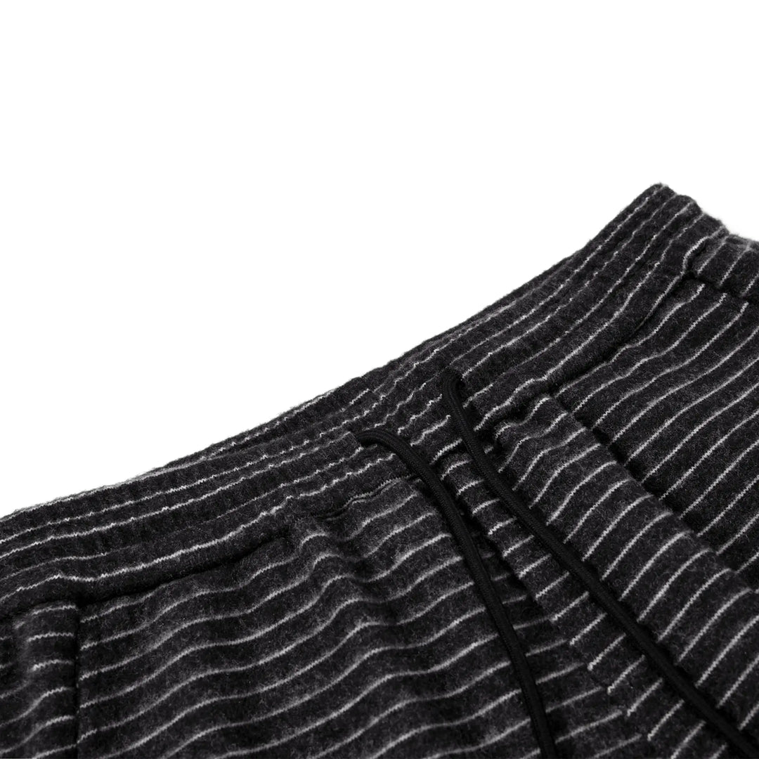 Close-up of dark grey knit trousers showing fine white pinstripes, high waist, elasticated waistband with a black drawstring.