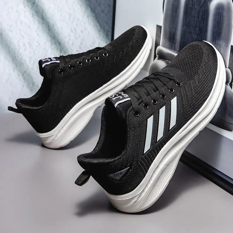 Pair of black Rhyzon men's breathable knit sneakers with white chevron stripes, white cushioned EVA midsole, and white rubber outsole, shown at a three-quarter angle.