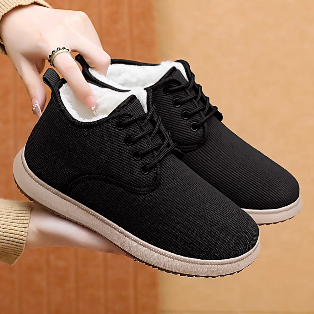 Pair of black Rhyzul women's casual winter boots with a fine-wale corduroy-like textured upper, plush faux fur lining, and beige soles, shown in a three-quarter view.