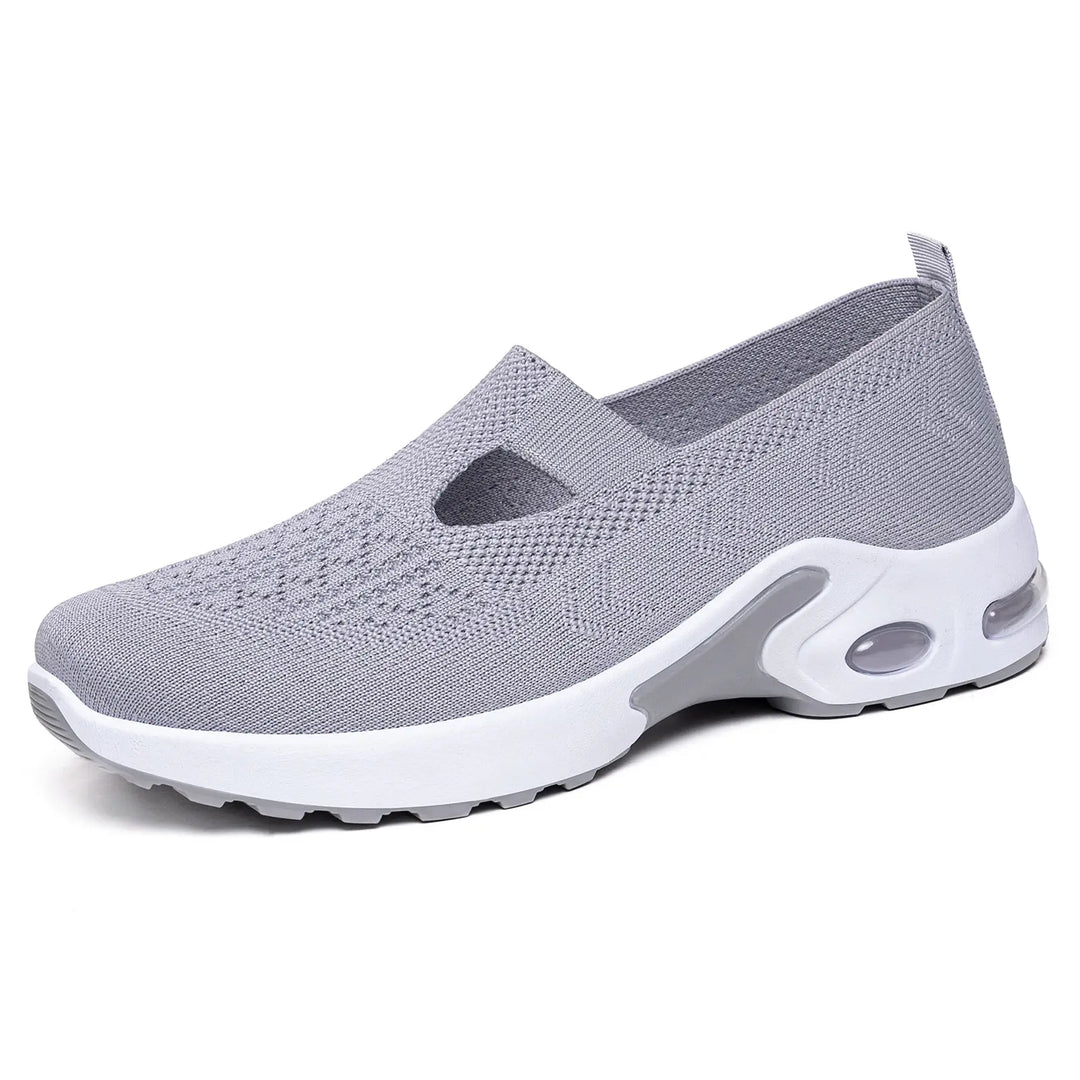 Grey breathable knit slip-on sneaker featuring a round toe, white midsole with a grey heel accent, and a visible air cushion bubble for comfort and style.