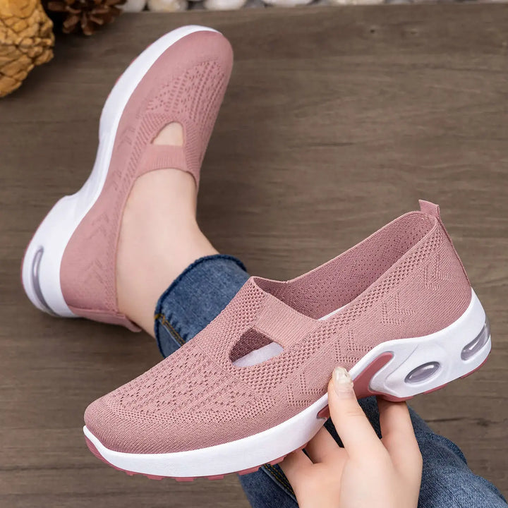 Close-up lifestyle view of dusty rose pink Rilux breathable knit slip-on sneakers with air cushion soles, shown on a foot with denim and being held to display detail.