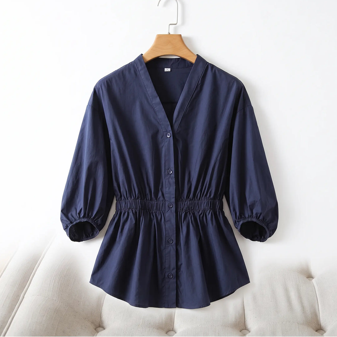 Navy blue Rixal V-neck cotton blouse with a cinched elasticated waist and voluminous bubble sleeves, button-front closure, displayed on a hanger against a neutral studio background.