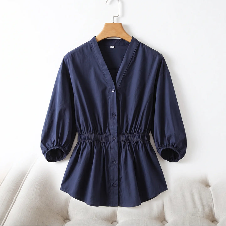 Navy blue Rixal V-neck cotton blouse with a cinched elasticated waist and voluminous bubble sleeves, button-front closure, displayed on a hanger against a neutral studio background.