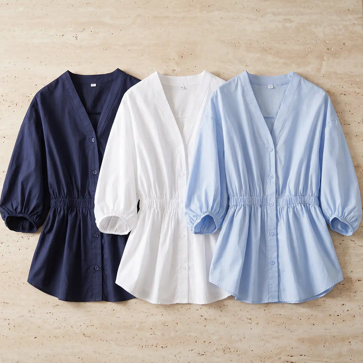 Three Rixal V-neck cotton blouses displayed side-by-side in navy blue, cloud white, and sky blue, featuring elasticated waists and voluminous bubble sleeves.