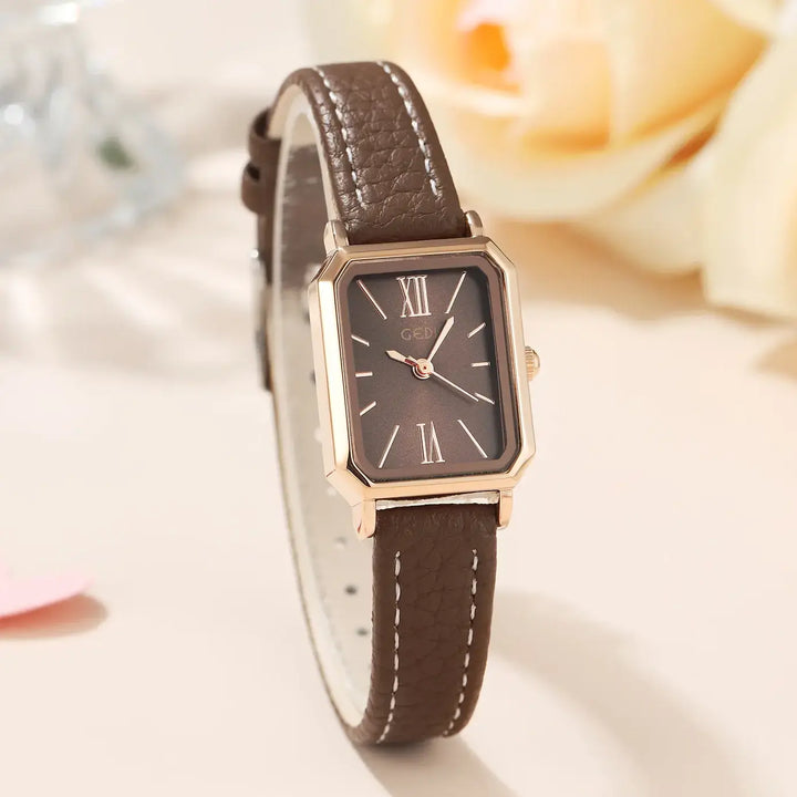 Elegant rose gold rectangular watch with a brown faux leather strap featuring white contrast stitching and a dark brown dial with Roman numerals.