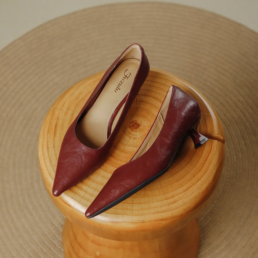 Pair of Rich Burgundy Rykon pointed-toe pumps with a flared kitten heel, made from smooth faux leather, presented on a textured mat.