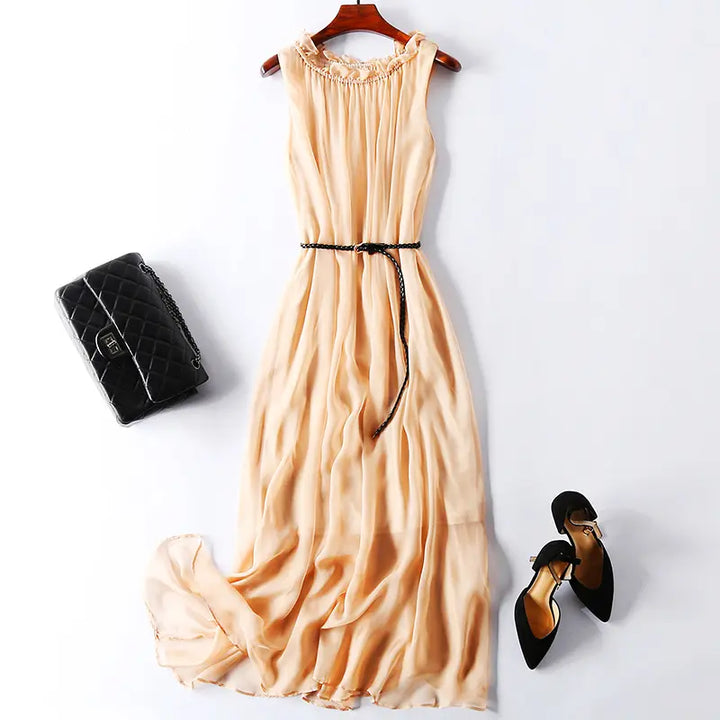 Muted grey pure silk midi slip dress with ruffled neckline and braided black belt, styled with a black quilted handbag and black high heels on a white background.
