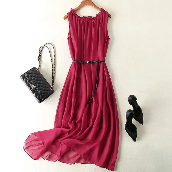 Deep crimson pure silk midi slip dress with a ruffled neckline and braided black belt, styled with a quilted handbag and black heels on a white background.